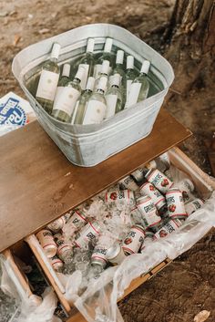 a cooler filled with bottles of beer sitting on top of a wooden table