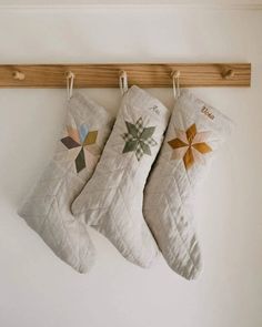 three christmas stockings hanging on a wooden rail