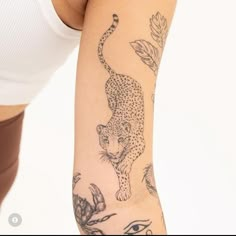 a woman's arm with tattoos on it and a cheetah in the background