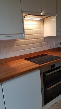 a kitchen with white cabinets and wooden counter tops