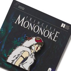 the princess mononoke brooch is sitting on top of a black book cover