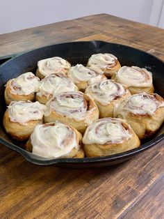 a pan filled with cinnamon rolls on top of a wooden table