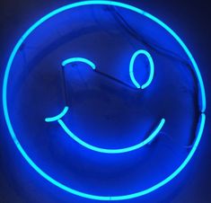 a blue neon sign with a smiley face on it's side and the letters o are lit up