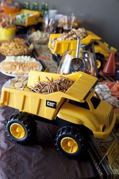 a table filled with lots of food and toy trucks on top of eachother