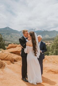 a bride and groom standing on top of a mountain