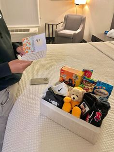 a person is reading a book on a bed with stuffed animals and books in it