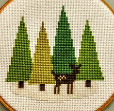 a cross stitch picture of some trees and a deer