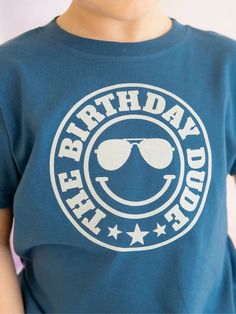 About this product The Birthday Dude Short Sleeve T-Shirt is a fun and festive t-shirt for celebrating the birthday boy! Features: Shirt Color: Indigo Graphic Color: White Material: 100% Cotton Features: Tagless inside neck label for an itch-free wear Fit: Toddler Unisex; True to Size Care: Machine washable, tumble dry low, wash with like colors Each t-shirt is hand pressed with love using baby and child safe inks. Details • Care Instructions: Machine wash • Fabric: 100% Cotton • Product Languag Fun T-shirt For Father's Day Birthday, Blue T-shirt For Father's Day Birthday, Fun Blue T-shirt For Father's Day, Funny Blue T-shirt For Birthday, Blue T-shirt With Funny Print For Birthday, Playful Crew Neck T-shirt For Birthday Gift, Blue T-shirt With Letter Print For Birthday Gift, Playful Crew Neck T-shirt For Father's Day, Funny Unisex T-shirt For Birthday