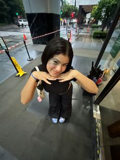 a woman standing in front of a glass door with her hands on her chest and looking at the camera