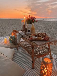 a table with food and candles on it at the beach