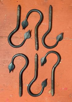 four metal hooks and screws sitting on top of a wooden table next to each other