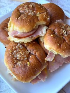 four ham and cheese sliders on a white plate