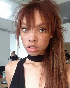 a woman with freckles on her face is posing for the camera while wearing a halter top