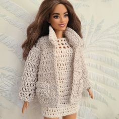 a doll is wearing a crocheted sweater and shorts with her hair pulled back