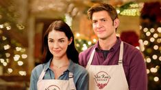 a man and woman standing next to each other in front of christmas trees with lights