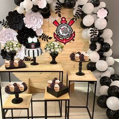 a table topped with cupcakes and black and white balloons in front of a wall