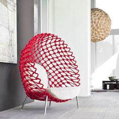 a red and white chair sitting in front of a window next to a painting on the wall