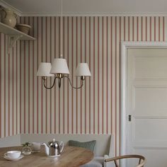 a dining room with striped wallpaper on the walls and wooden table in between two chairs