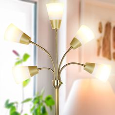 a floor lamp with five lights on it in front of a window and potted plant