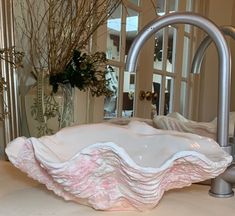 a large white bowl sitting on top of a counter next to a vase filled with flowers