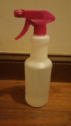 a pink spray bottle sitting on top of a wooden floor