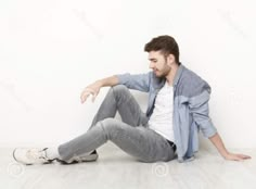 a young man sitting on the floor with his legs crossed and looking at something in front of him