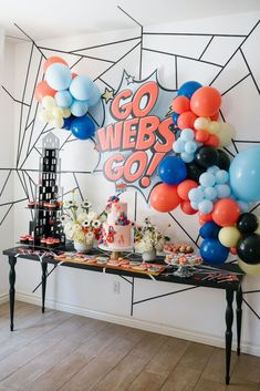 a party table with balloons, cake and confetti on it in front of a wall that says go webbs go