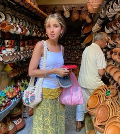 a woman standing next to a man in a store filled with lots of pots and pans