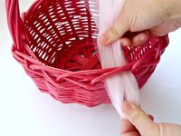 a person is pulling onions out of a red wicker basket with pink handles on a white surface