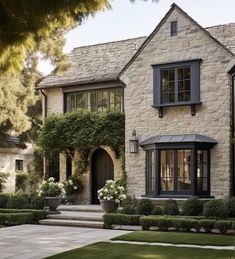 a large house with lots of windows and bushes in front of the door is surrounded by greenery