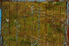 an old rusty gate in the middle of a field with grass and weeds behind it