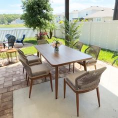 a table and chairs on a patio next to a fence with flowers in the vase