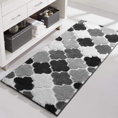 a white and black rug on the floor next to a cabinet with drawers in it