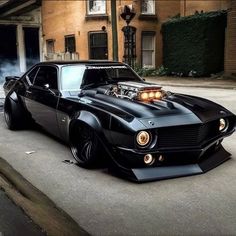 a black muscle car parked in front of a building