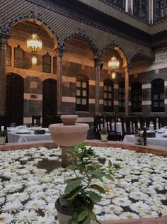 the interior of an old building with tables and flowers in the center, surrounded by arches