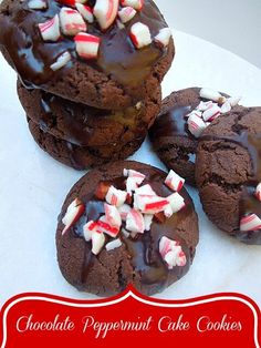 four chocolate cookies with candy canes and marshmallows are on a white plate