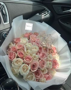 a bouquet of pink and white roses with a tiara in the middle of it