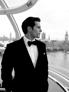 a man in a tuxedo looking out over the water