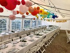 tables and chairs are set up in a tent with paper lanterns hanging from the ceiling