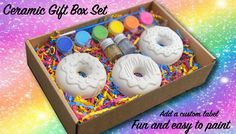 a box filled with donuts covered in icing and sprinkles on top of a rainbow colored background