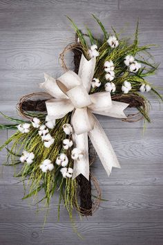 a wreath with white flowers and grass on a wooden surface, ready to be used as an ornament