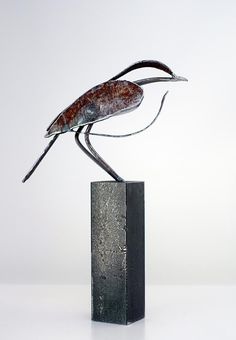 a sculpture of a bird sitting on top of a metal block