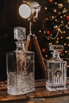 two decante bottles sitting next to each other on a table near a christmas tree