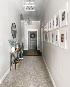 a long hallway with pictures on the wall and photos on the floor in front of it