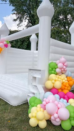 an inflatable pool with balloons on the ground next to it and a white fence