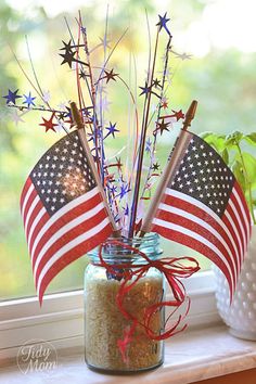 an american flag in a mason jar on a window sill next to a potted plant