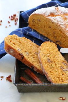 a loaf of bread sitting on top of a pan next to cinnamon sticks and an orange slice