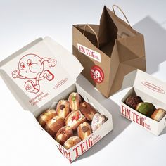 an open box of donuts next to another box with donuts in it on a white surface