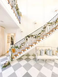 a white couch sitting under a staircase next to a bannister filled with greenery