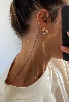 a woman holding up a cell phone to her ear with gold hoop earrings on it